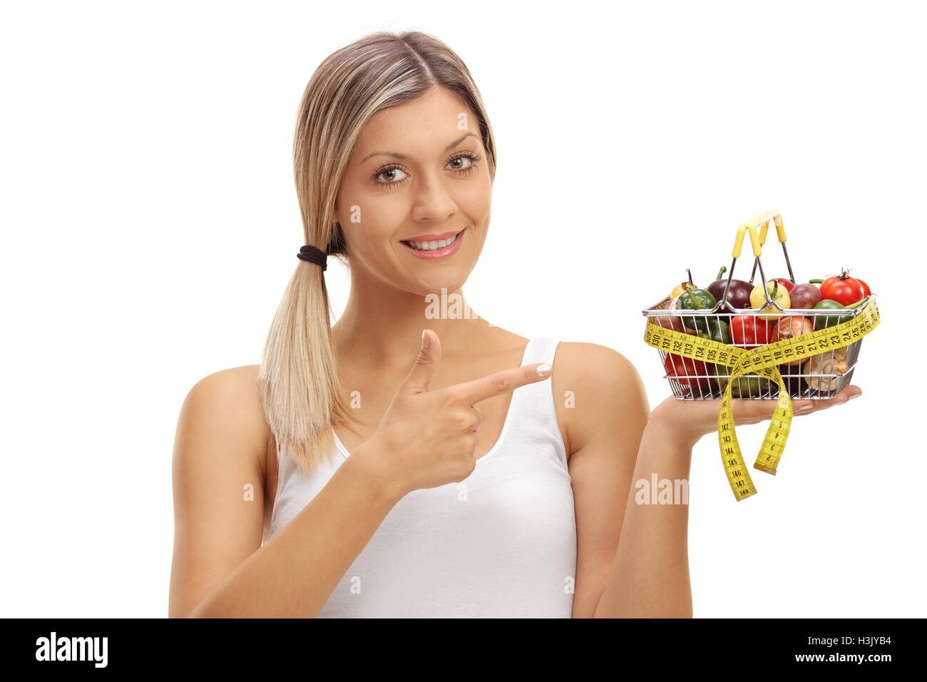 Joyful woman holding a small shopping basket full of fruits and ...