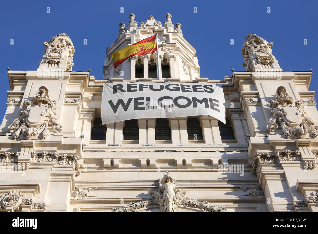 A banner welcoming refugees hangs from the Cybele Palace, Madrid's City Hall on the Plaza de Cibeles, Madrid, Spain Stock Photo