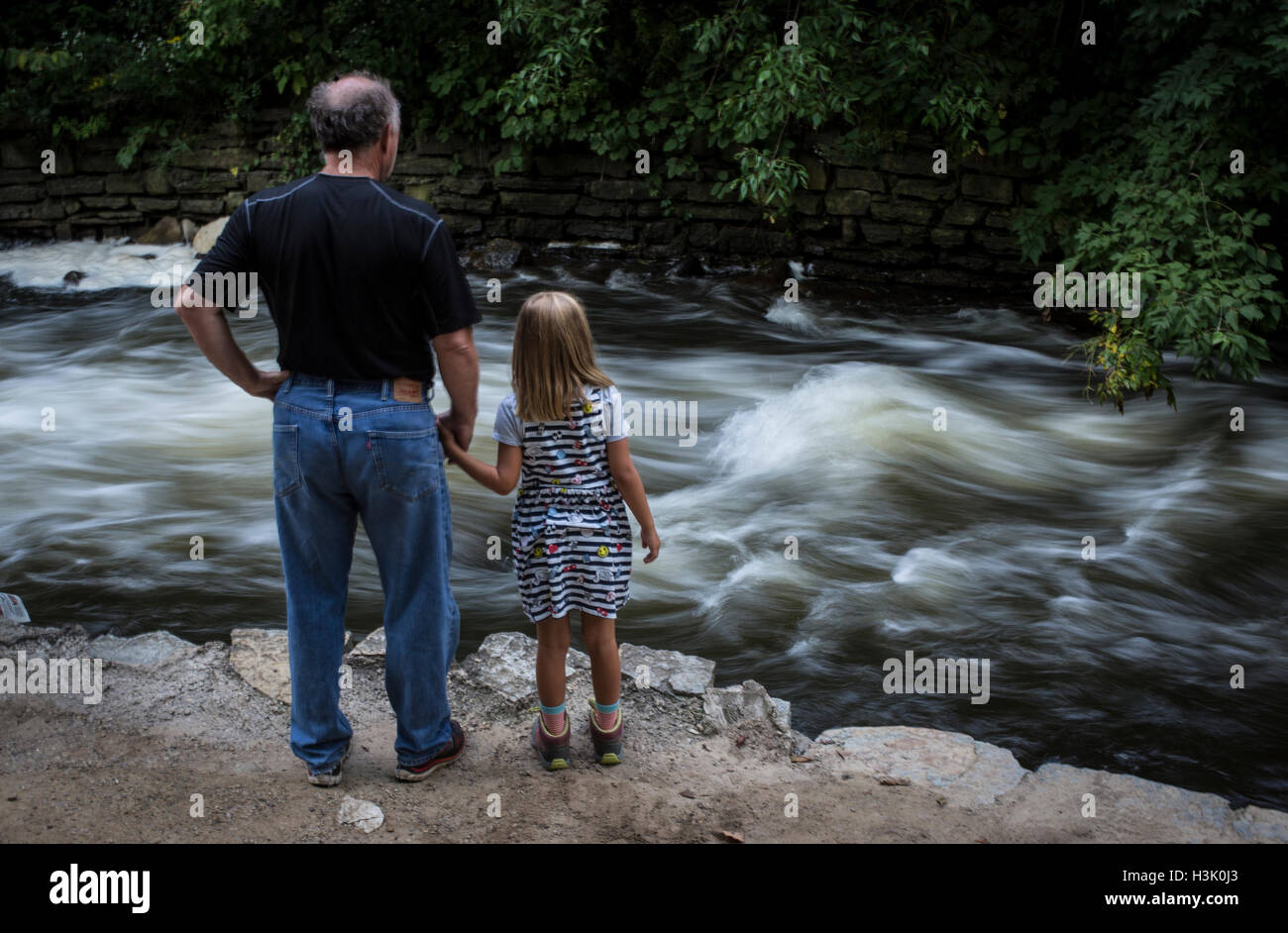 A grandfather holds his granddaughter's hand near Minnehaha Falls in Minnesota Stock Photo