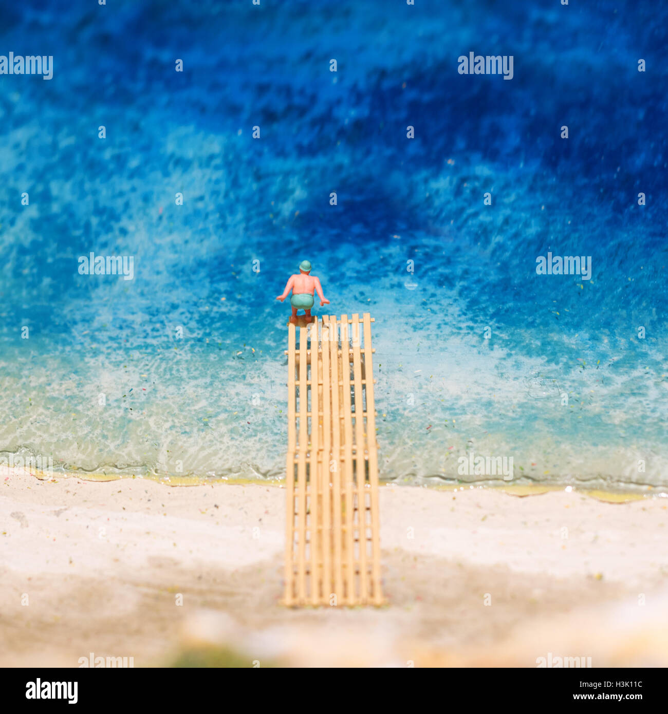 Miniature world: fat man jumping into water taking a holiday at the beach. Summer lifestyle, vacation and tourism concept Stock Photo