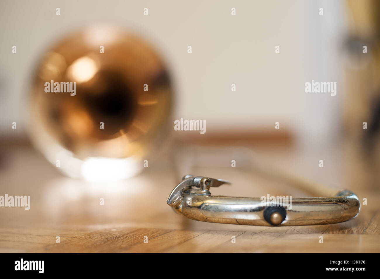 Trombone bell on brown wooden parquet, water key valve detail selective