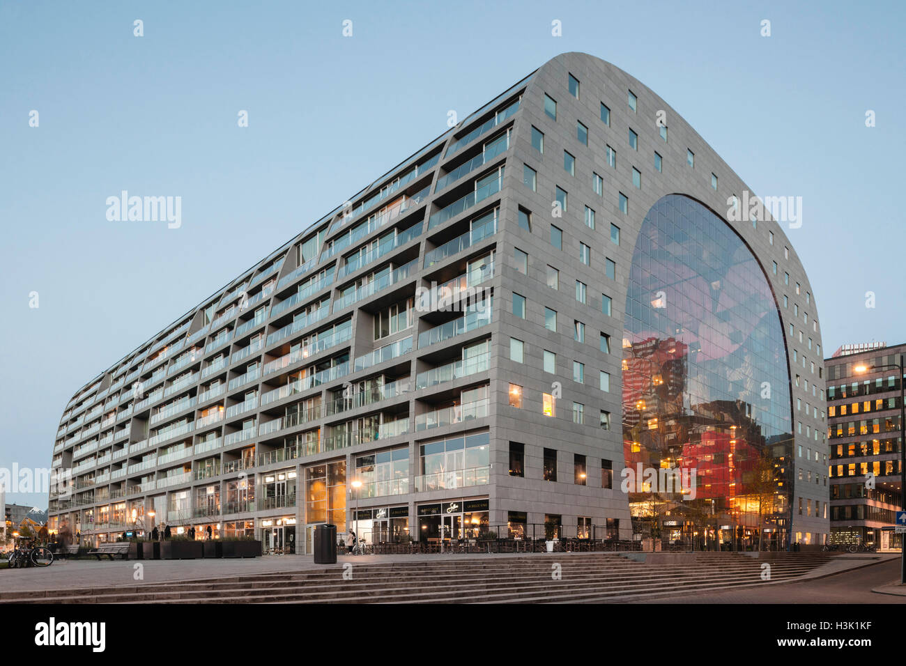 Side elevation of curved building with context and passersby on public square. Market Hall Rotterdam, Rotterdam, Netherlands. Architect: MVRDV, 2014. Stock Photo