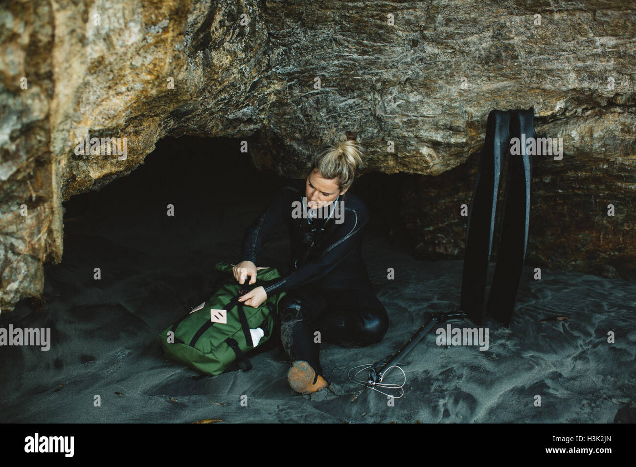 Diver with speargun resting on beach, Big Sur, California, USA Stock Photo