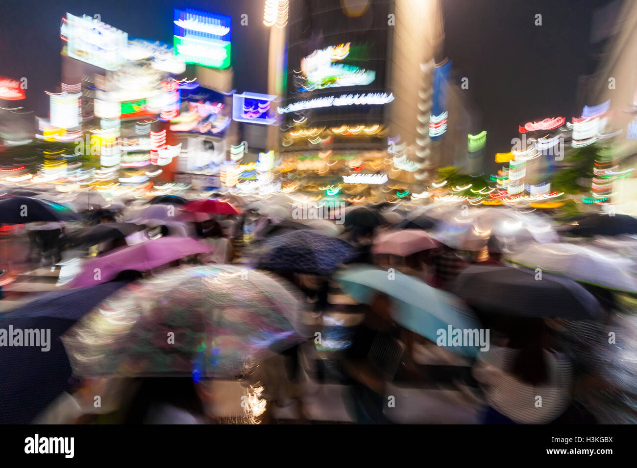Motion blurred people with umbrellas in the rain at night on the ...