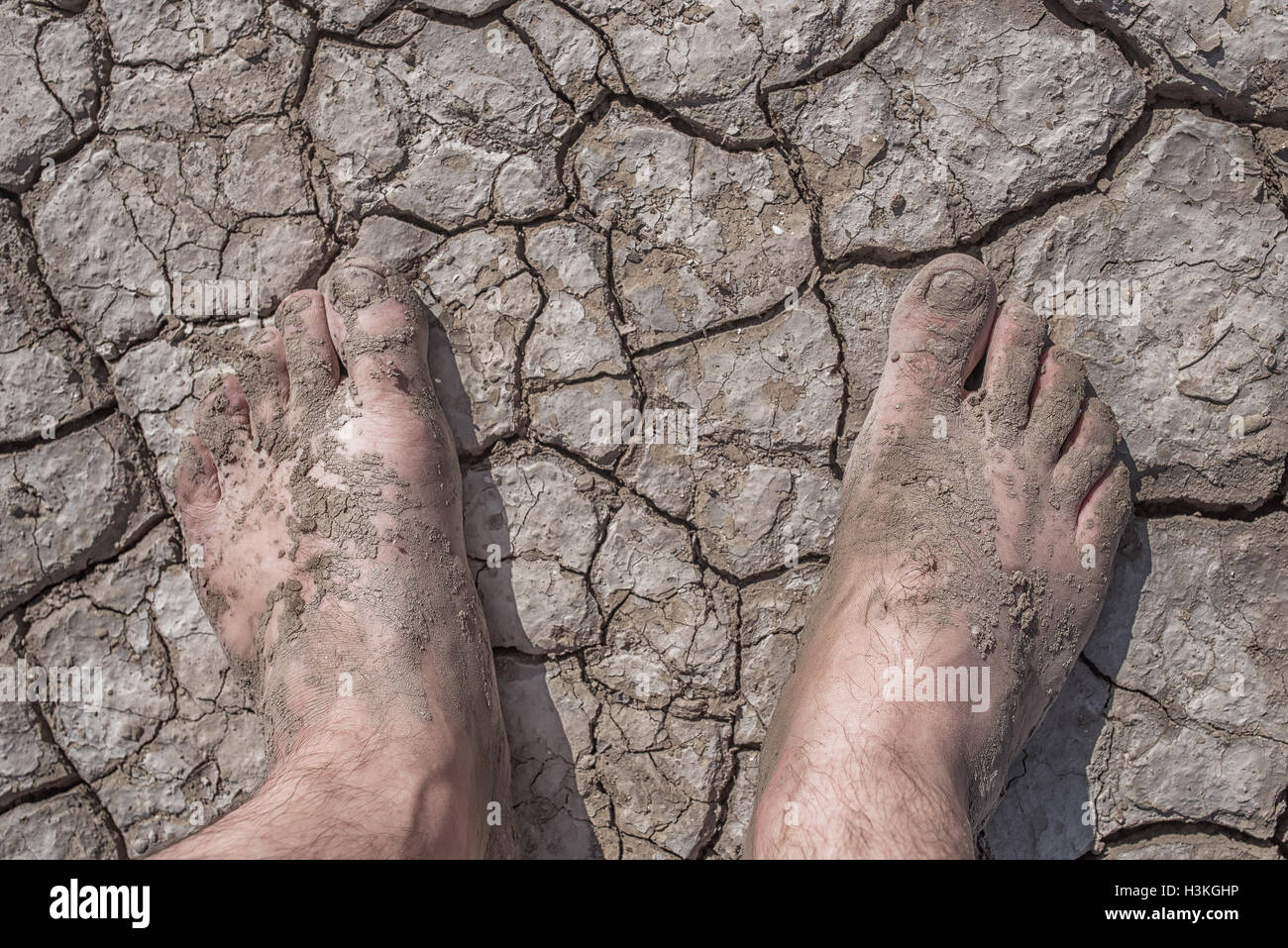 The cracked soil ground and man feet Stock Photo
