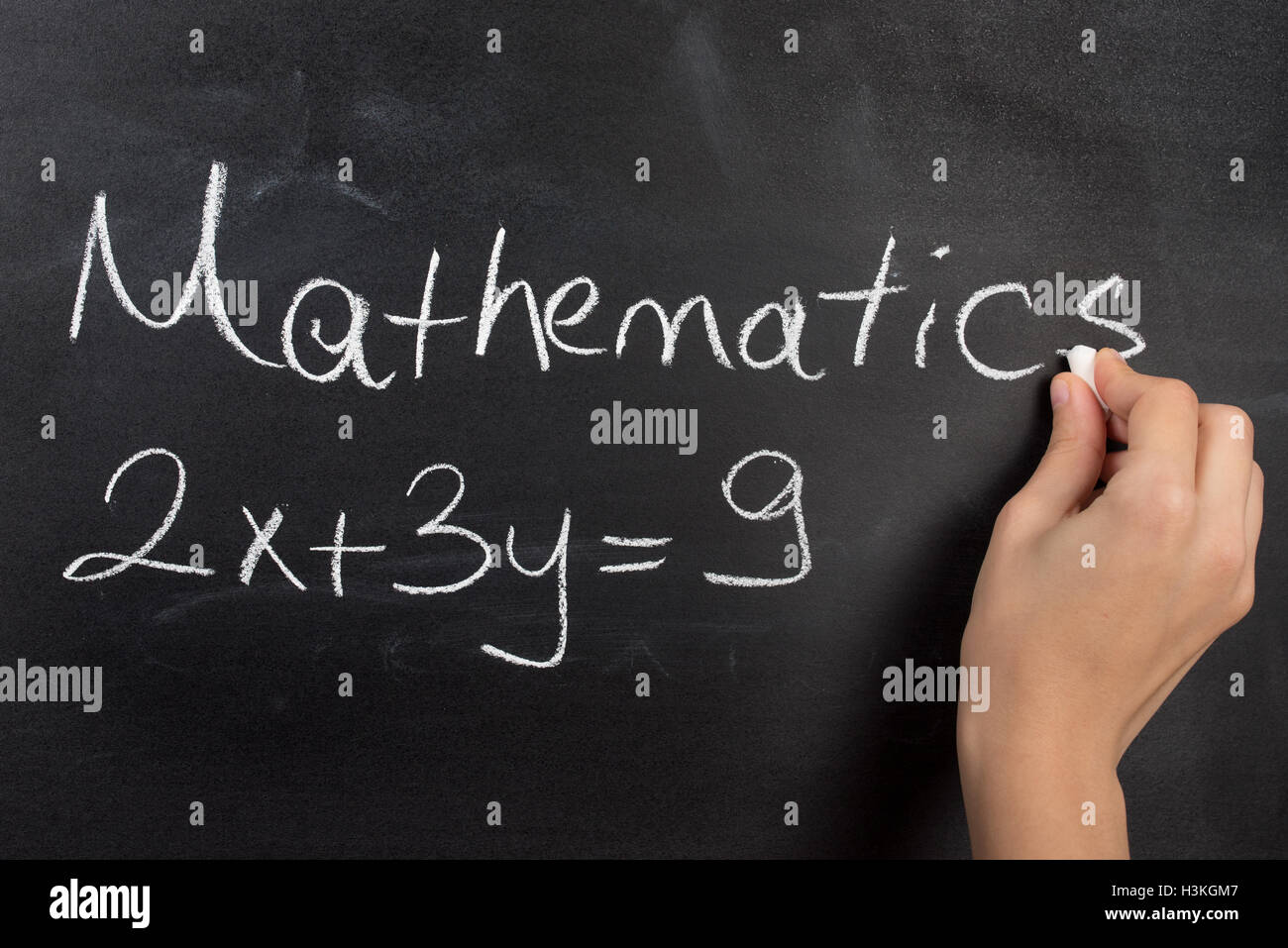 Closeup of hand writing complicated math equation on black board. Stock Photo