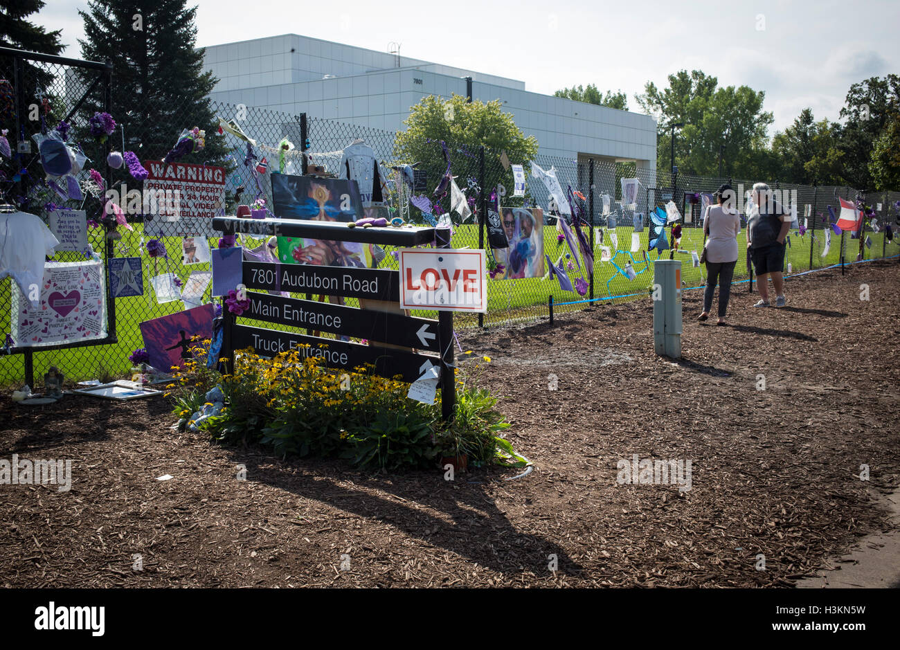 two people look at Prince memorabilia attached to a fence outside Paisley Park Studios in Chanhassen, Minnesota Stock Photo