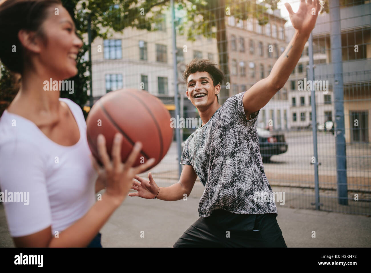 Young woman taking shot with man blocking on basketball court