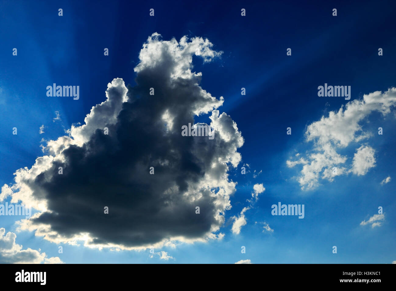 Blue sky with sunbeams shining through the dark cloud. Stock Photo