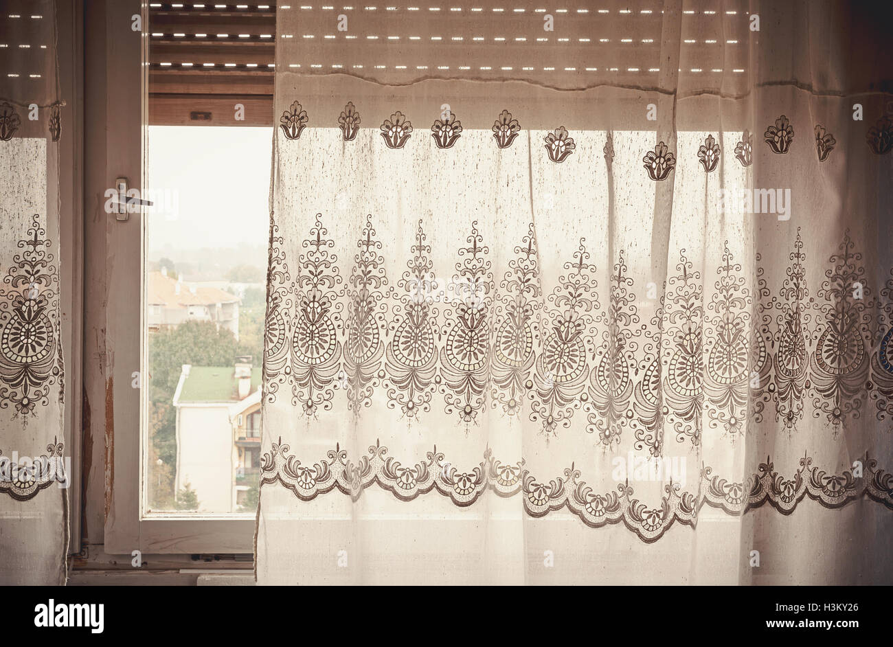 Part of an old curtain, details of an embroidery decoration, window in the back, day time. Stock Photo