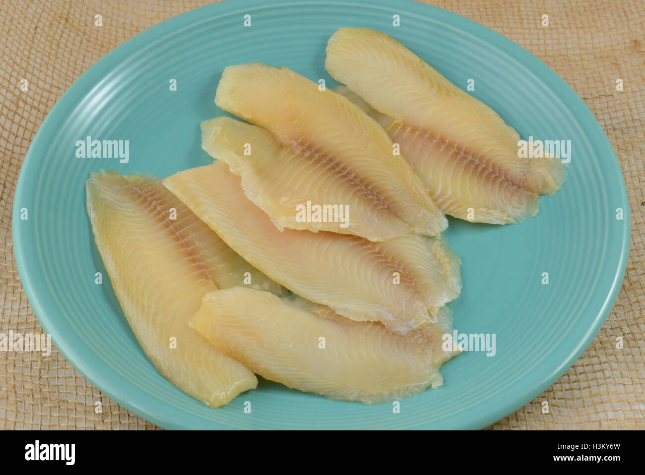 Frozen tilapia fish fillets thawing on blue plate Stock Photo Alamy