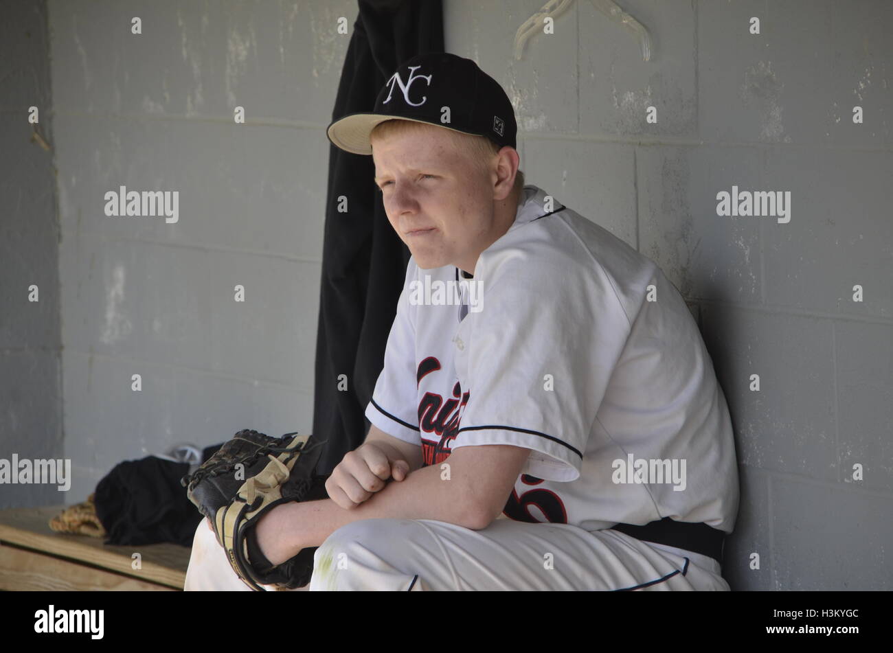 teenage baseball player sitting in dugout Stock Photo Alamy