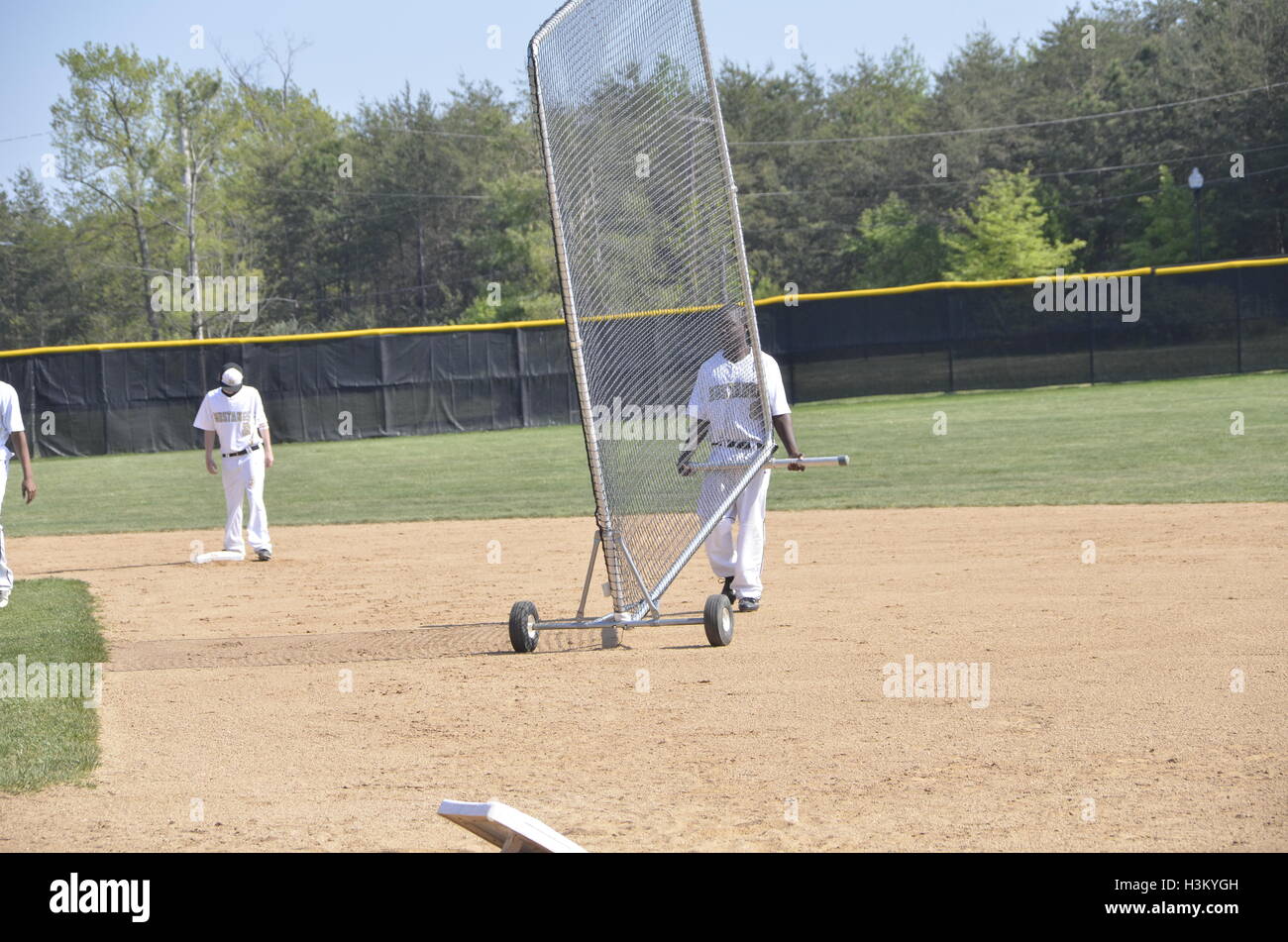Players preparing for baseball game by removing a batters box Stock