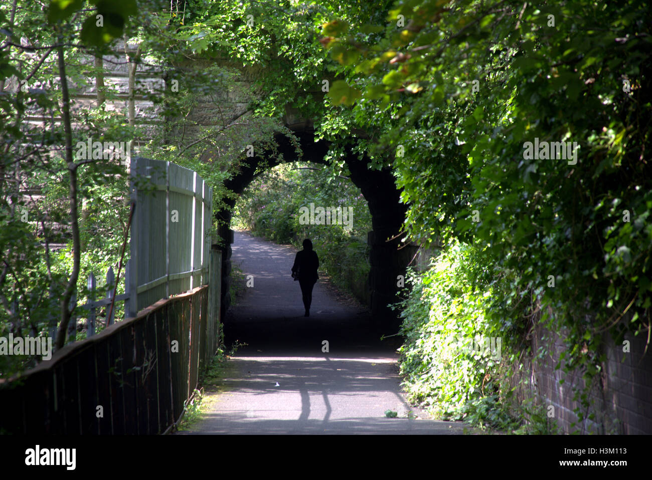 silhouettes of people in the city against the background of the entrance at bridge tunnel in the west end of Glasgow in the park Stock Photo
