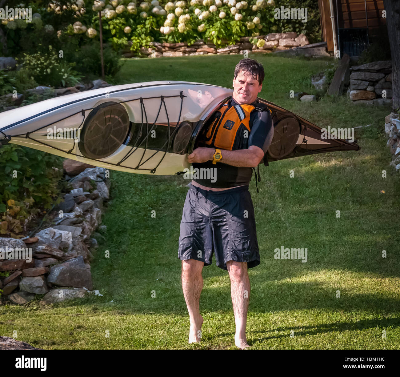 man transporting a kayak toward a lake Stock Photo