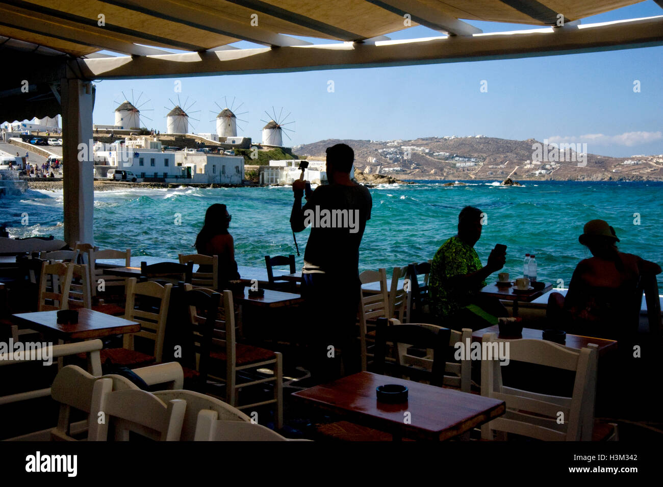 View of windmills from seaside cafe in Mykonos Stock Photo