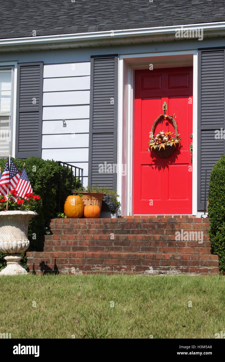 Autumn decorations at the entrance of a house. Harvest basket hanging on red door. Stock Photo