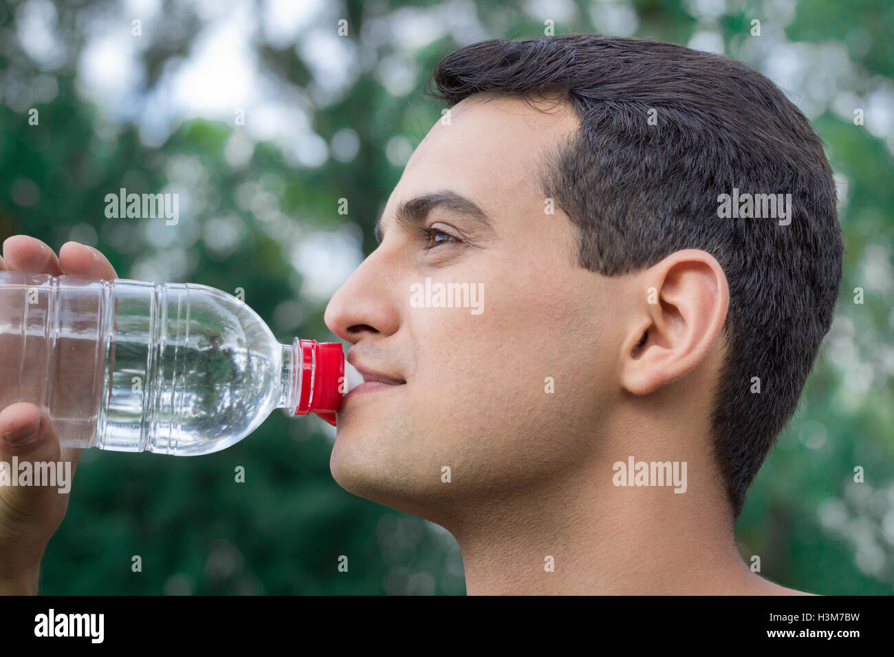 Young fitness man drinks water during training workout outdoor Stock Photo