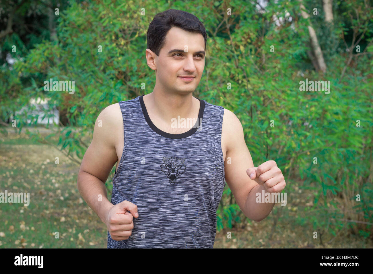 Young fitness man runs during his training workout in park outdoor Stock Photo