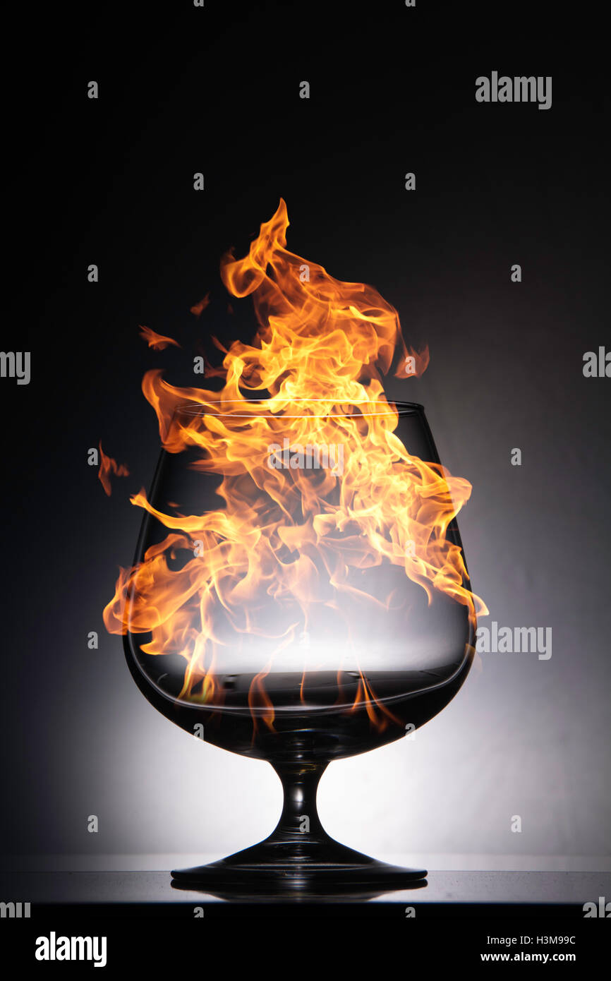 Burning glass with raging flames on a black background Stock Photo