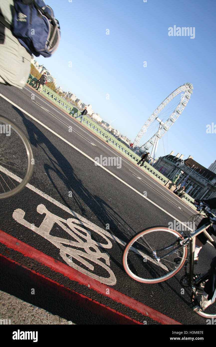 Cyclist rides along bicycle path on Westminster Bridge, with London Eye wheel in the background. Sunny morning in October. © Pau Stock Photo