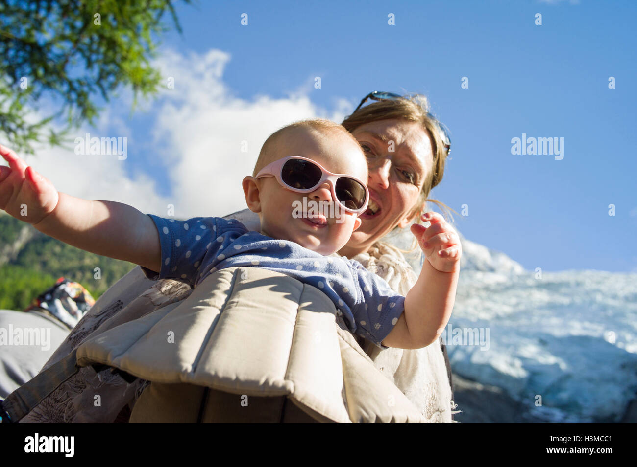 Low angle view of baby girl in sling sticking tongue out at camera Stock Photo
