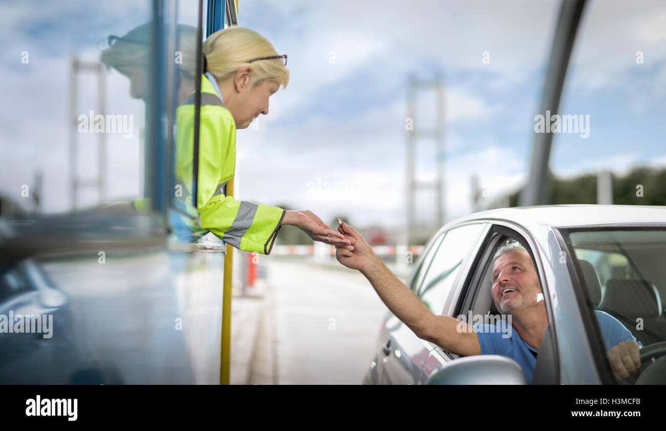 Driver in car paying toll booth at bridge Stock Photo