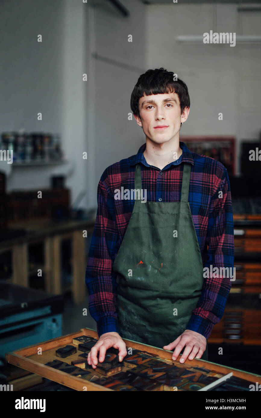 Portrait of young craftsman next to tray of letterpress letters in print workshop Stock Photo