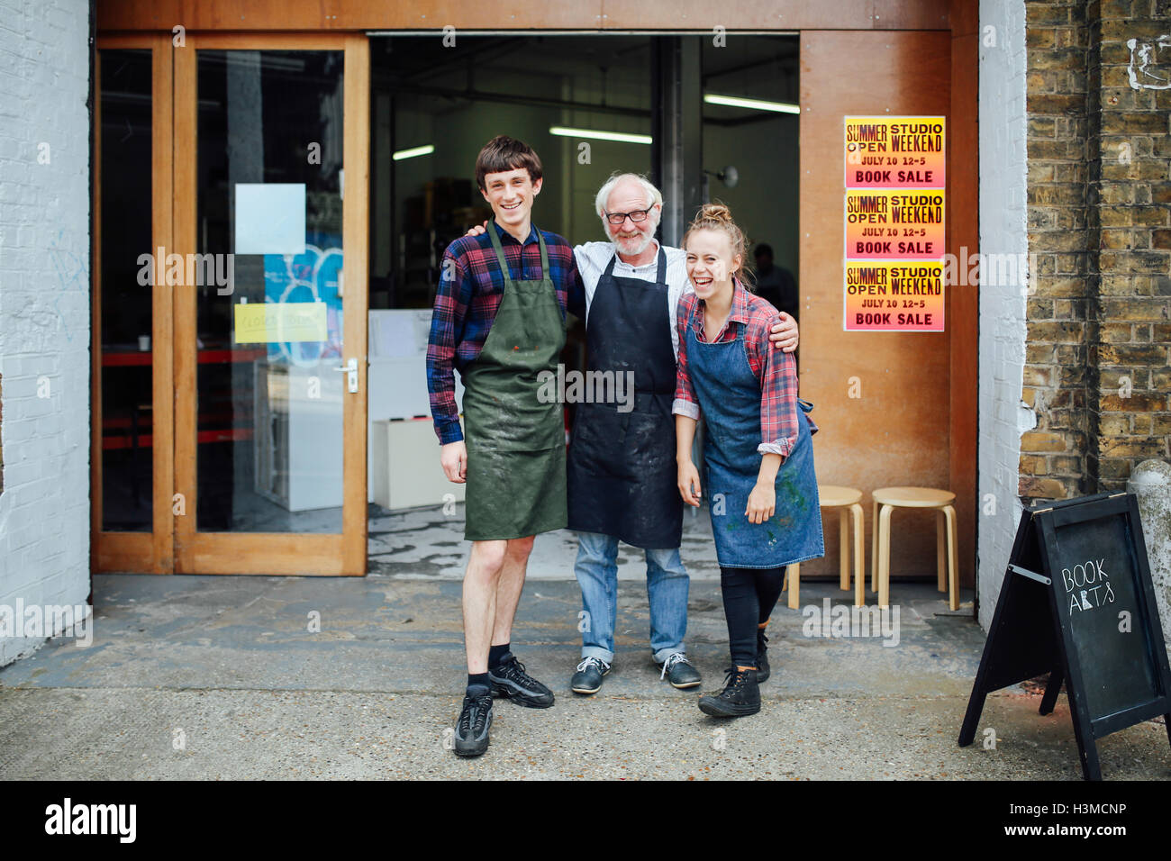 Family portrait of senior craftsman with daughter and son outside print workshop Stock Photo