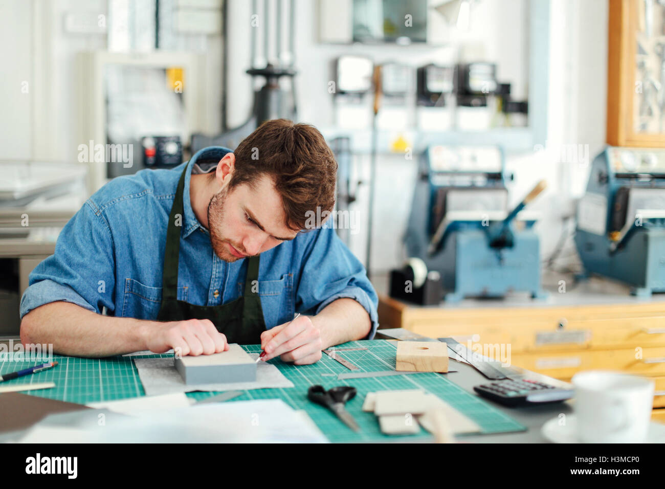 Young craftsman using scalpel and making work in print studio Stock Photo