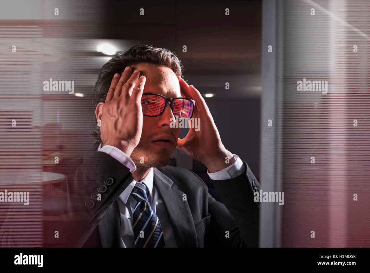 Composite image of businessman at computer screen with graphical data reflected in glasses Stock Photo