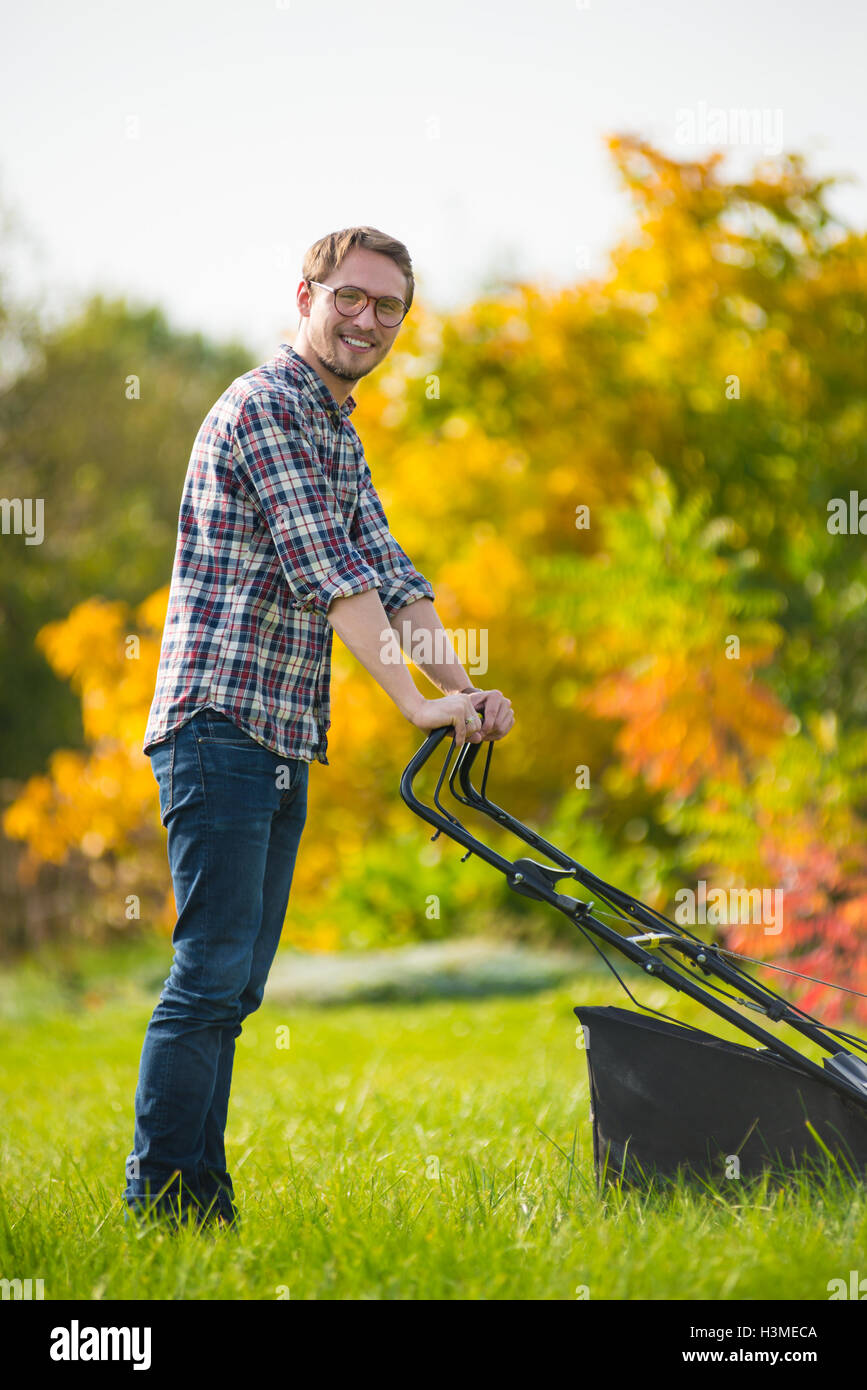 Young man is mowing the lawn on a nice sunny day. Stock Photo