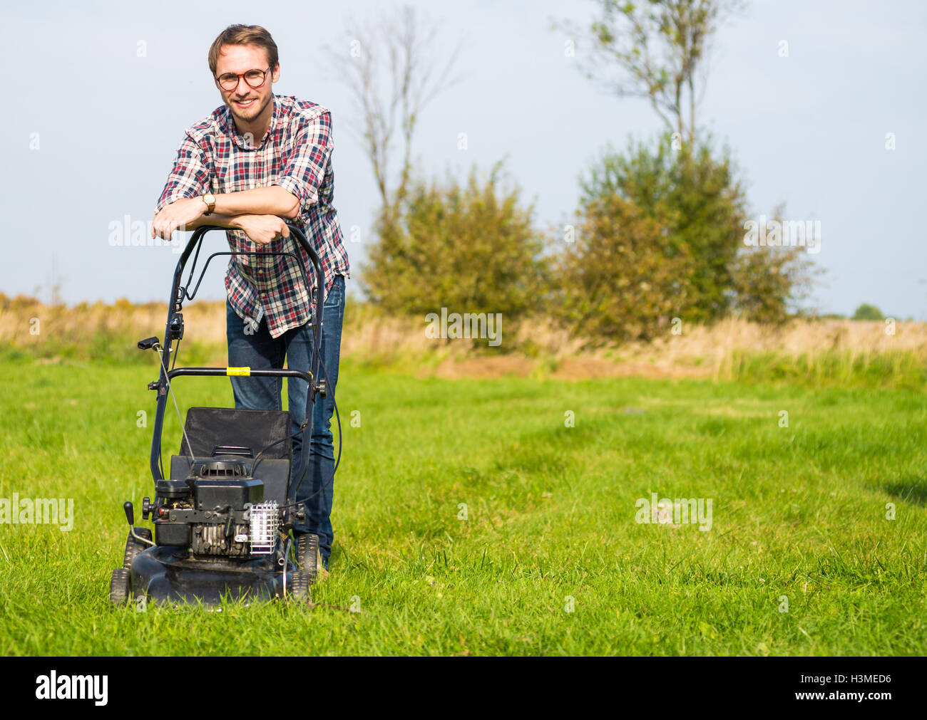 Young man is mowing the lawn on a nice sunny day. Stock Photo