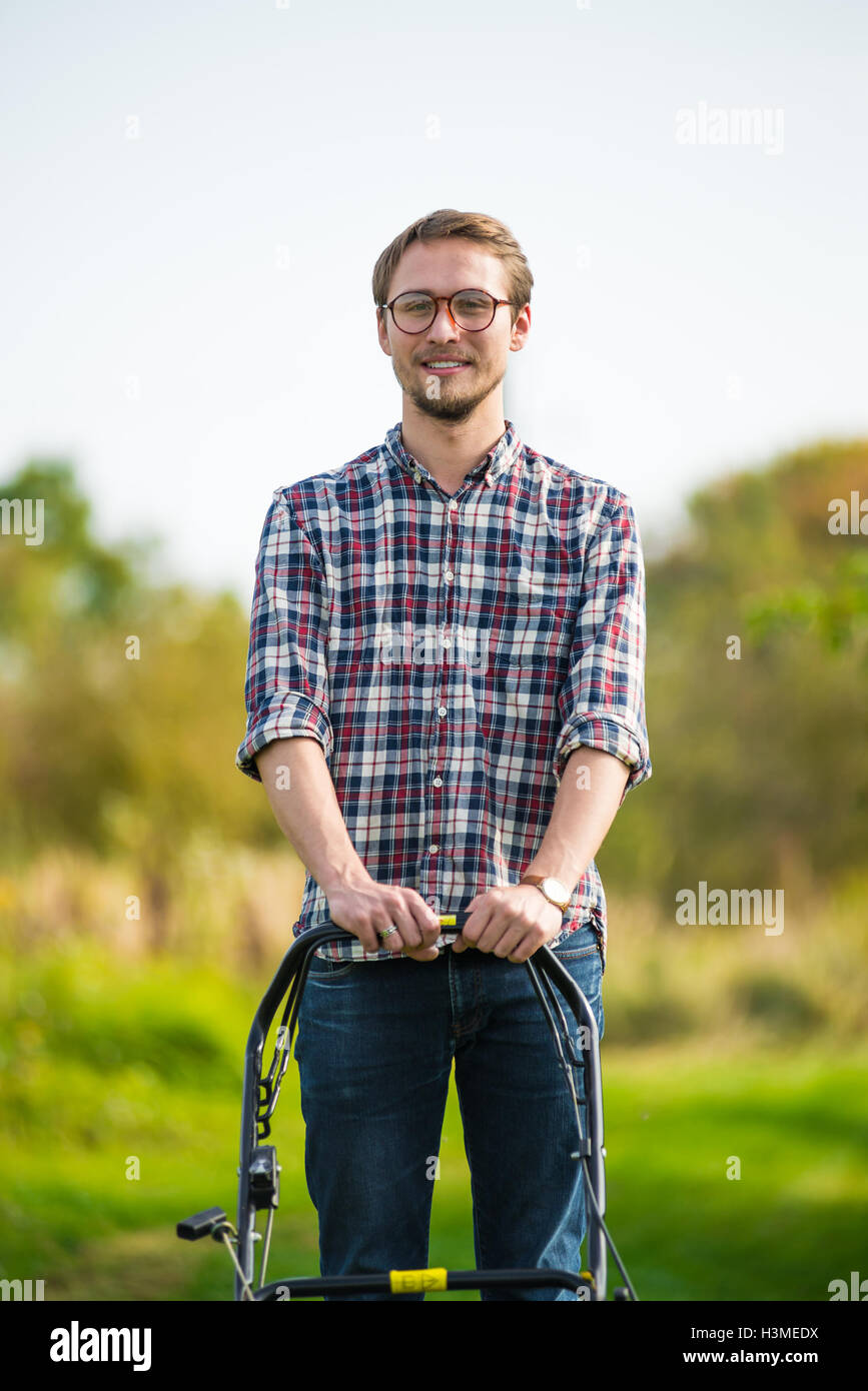 Young man is mowing the lawn on a nice sunny day. Stock Photo