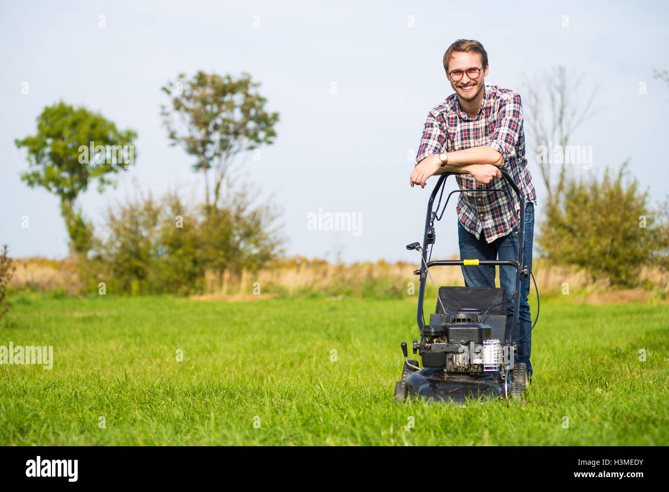 Young man is mowing the lawn on a nice sunny day. Stock Photo