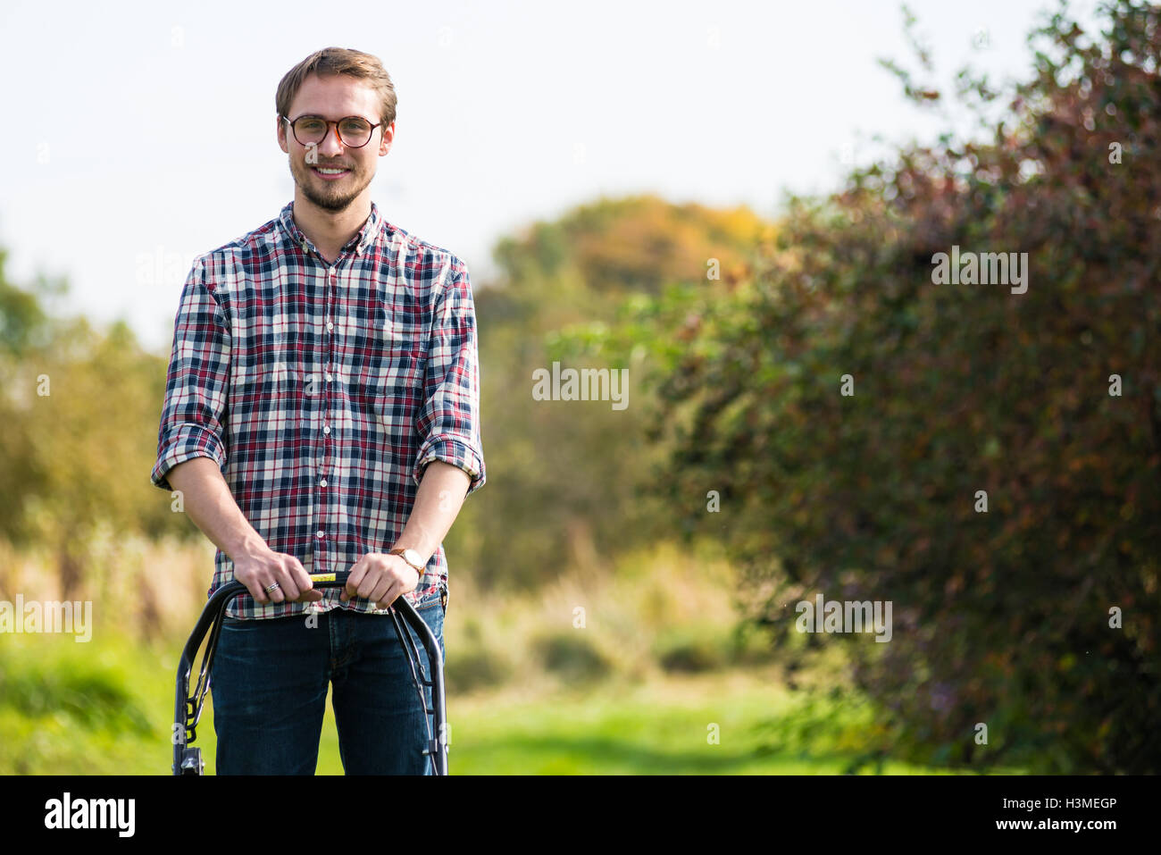 Young man is mowing the lawn on a nice sunny day. Stock Photo