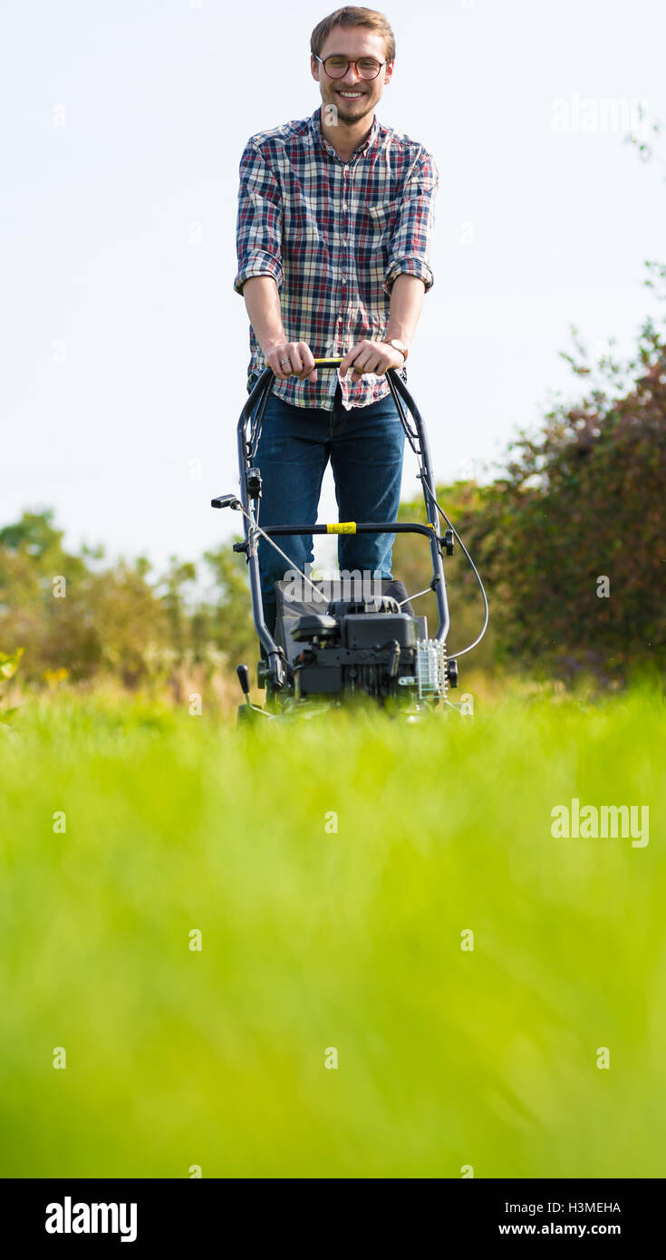 Young man is mowing the lawn on a nice sunny day. Stock Photo