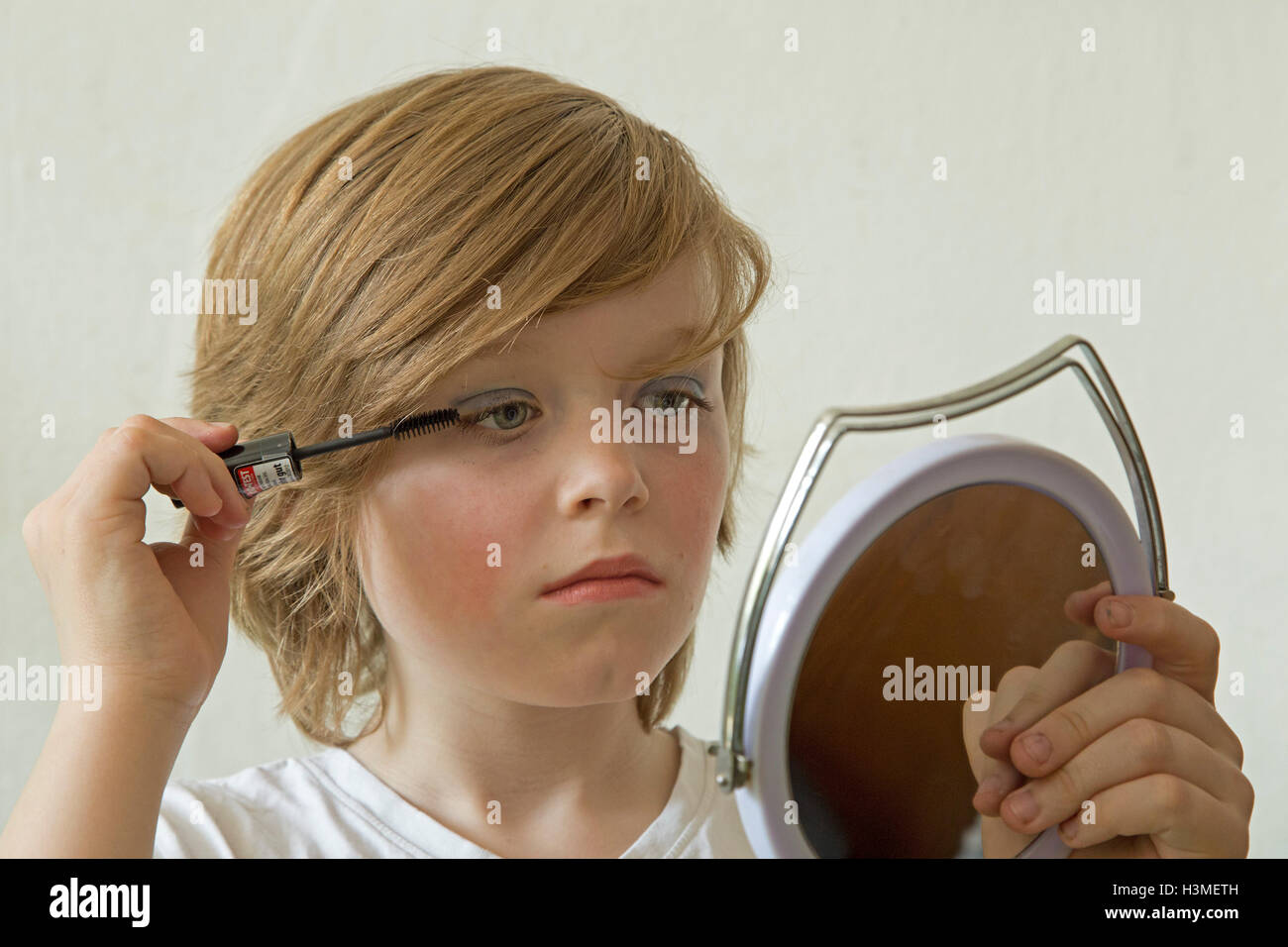 young boy putting makeup on pretending to be a girl Stock Photo