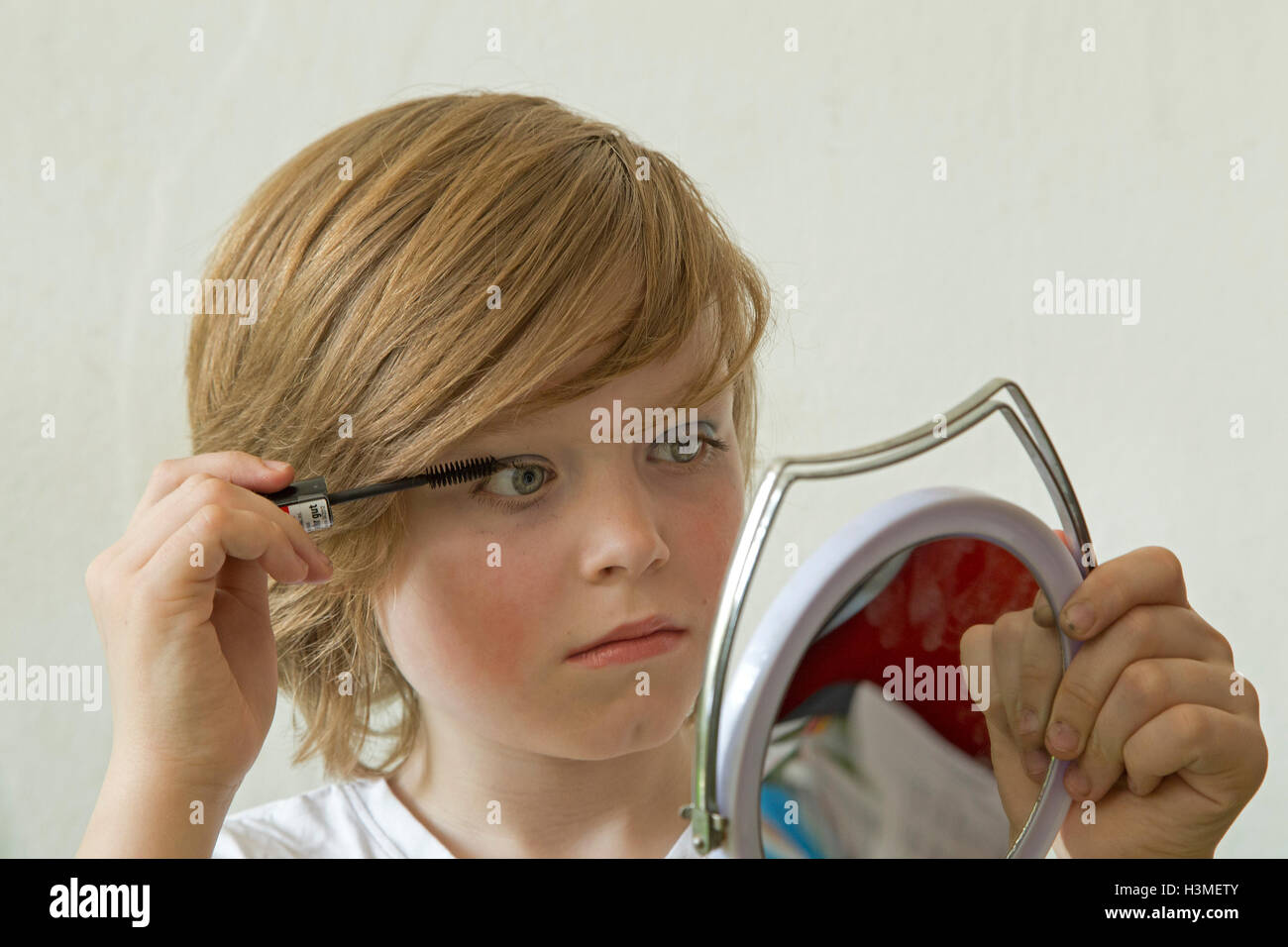 young boy putting makeup on pretending to be a girl Stock Photo