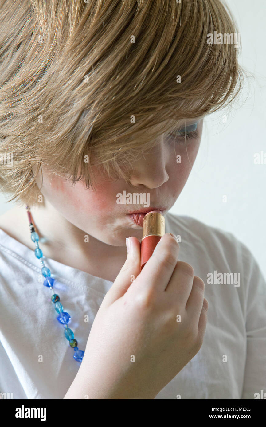 young boy putting on lipstick pretending to be a girl Stock Photo