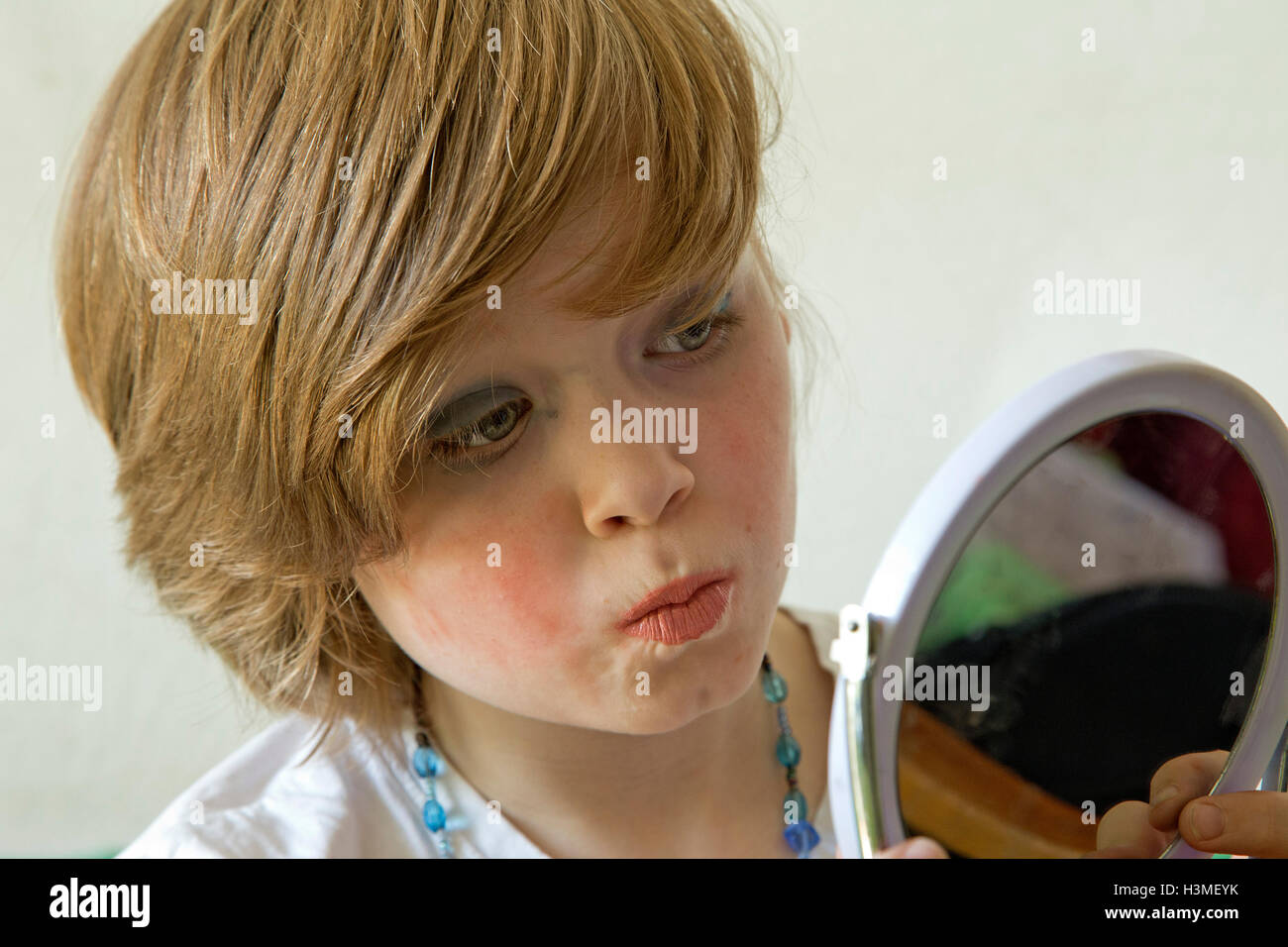 young boy putting makeup on pretending to be a girl Stock Photo