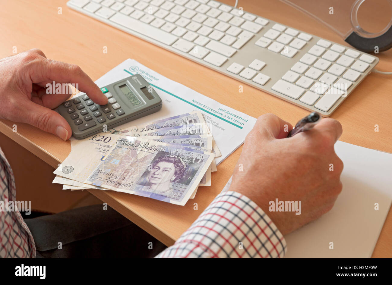 Close up of businessman man person completing HMRC self assessment tax return calculator and