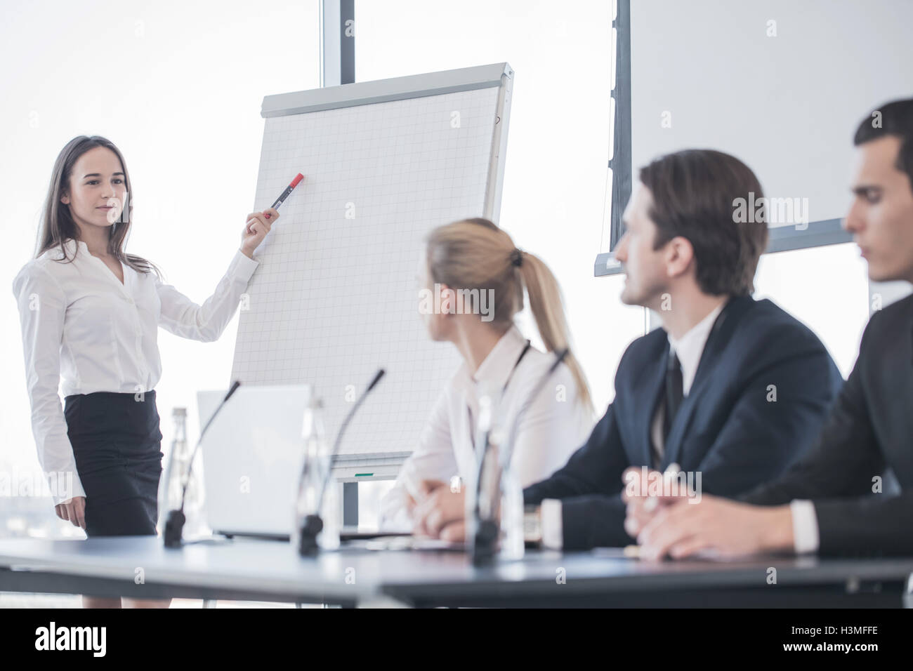 Business woman speaking at presentation and pointing to white board Stock Photo