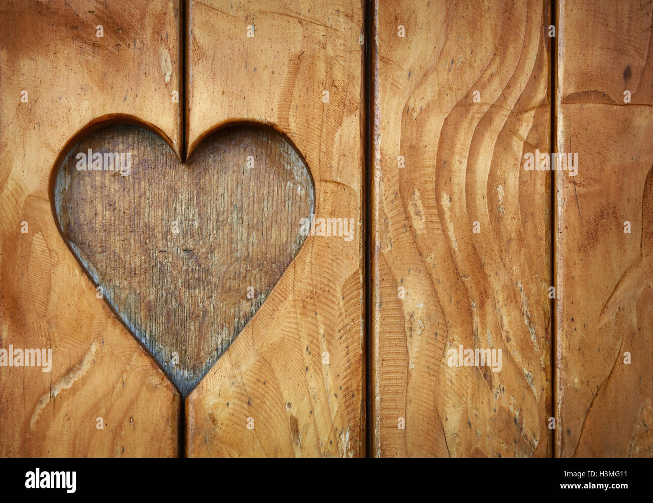 One heart shape, symbol of love and romance, wood carved cut in vintage old grunge natural brown wooden planks texture backgroun Stock Photo