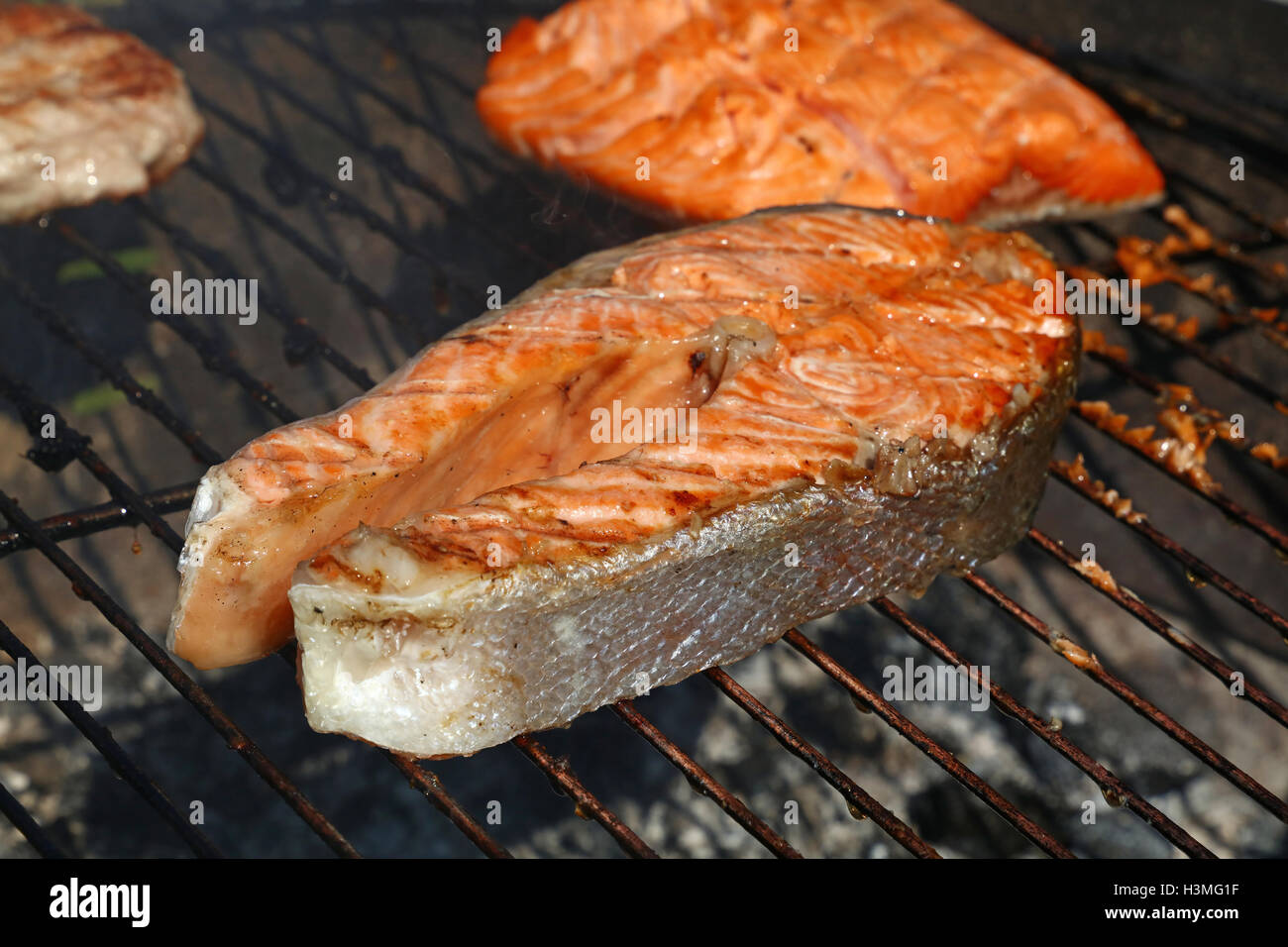 Grilled salmon fish steak barbecue meal cooking, prepared on bbq grill
