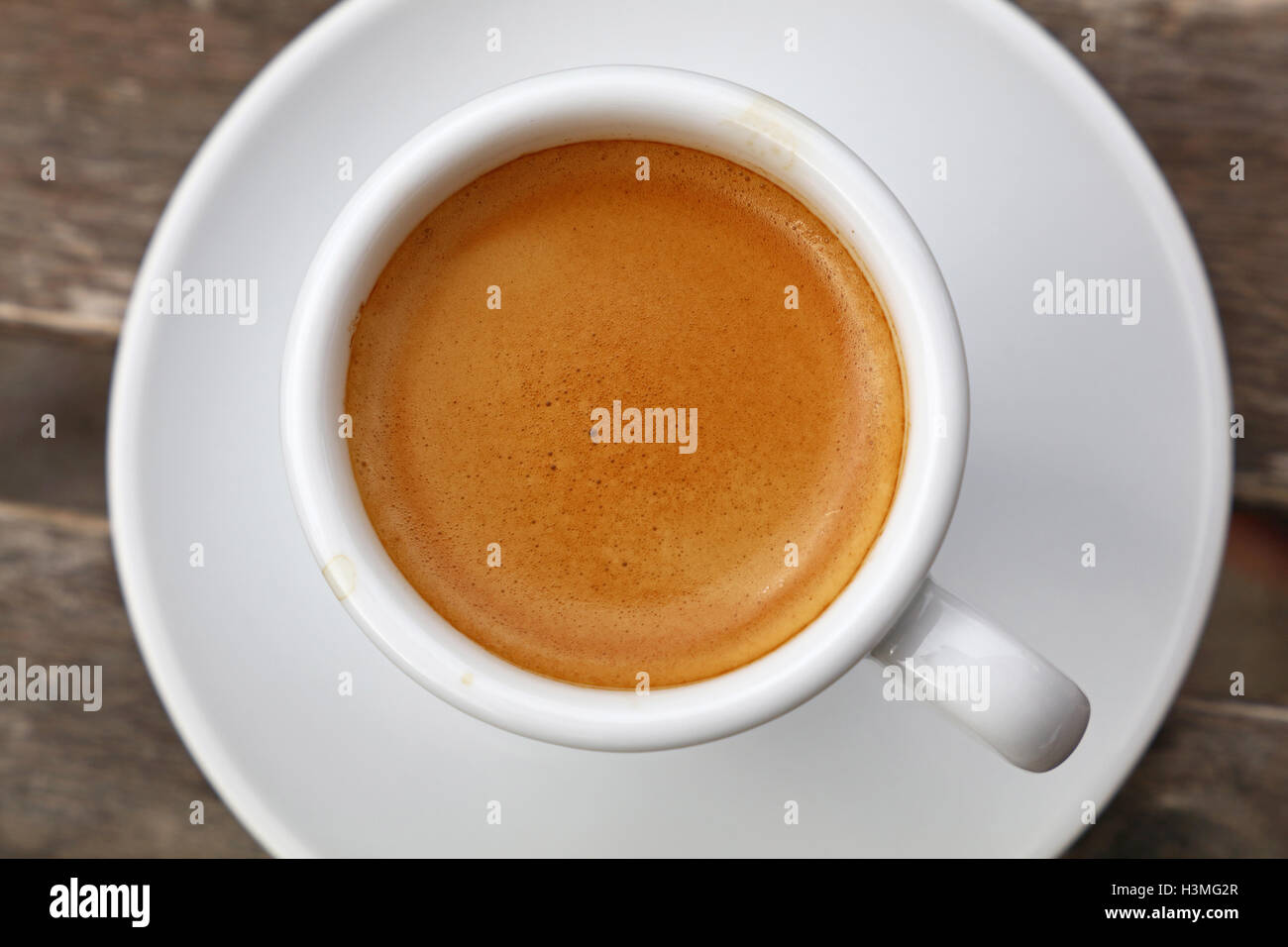 Espresso coffee shot brown crema froth in porcelain white cup with saucer  over wooden table, detail close up, elevated top view Stock Photo - Alamy