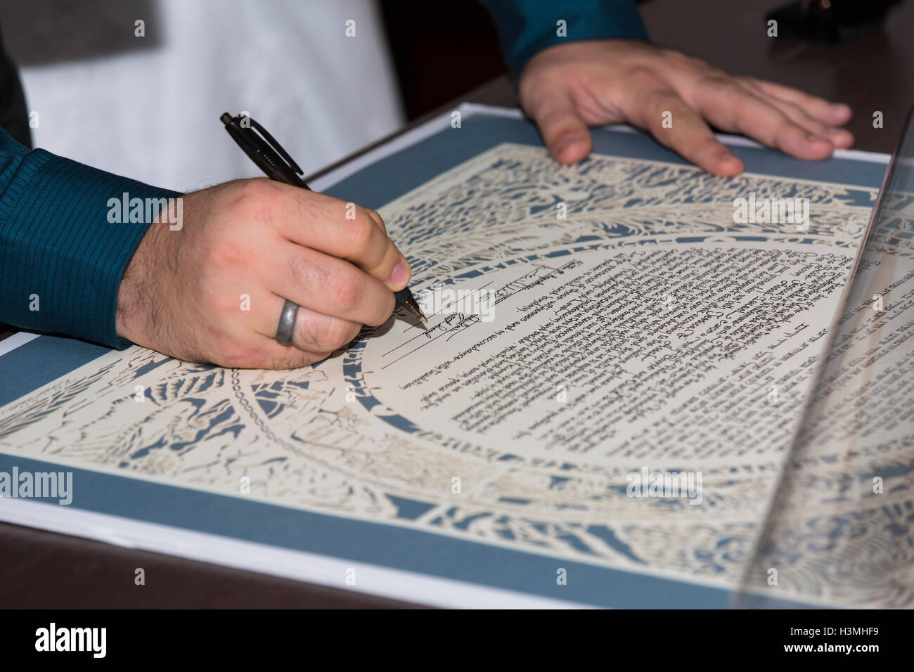 Bride and groom signing the ketubah or wedding contract outlining rights and obligations at a Jewish wedding in a close up view Stock Photo