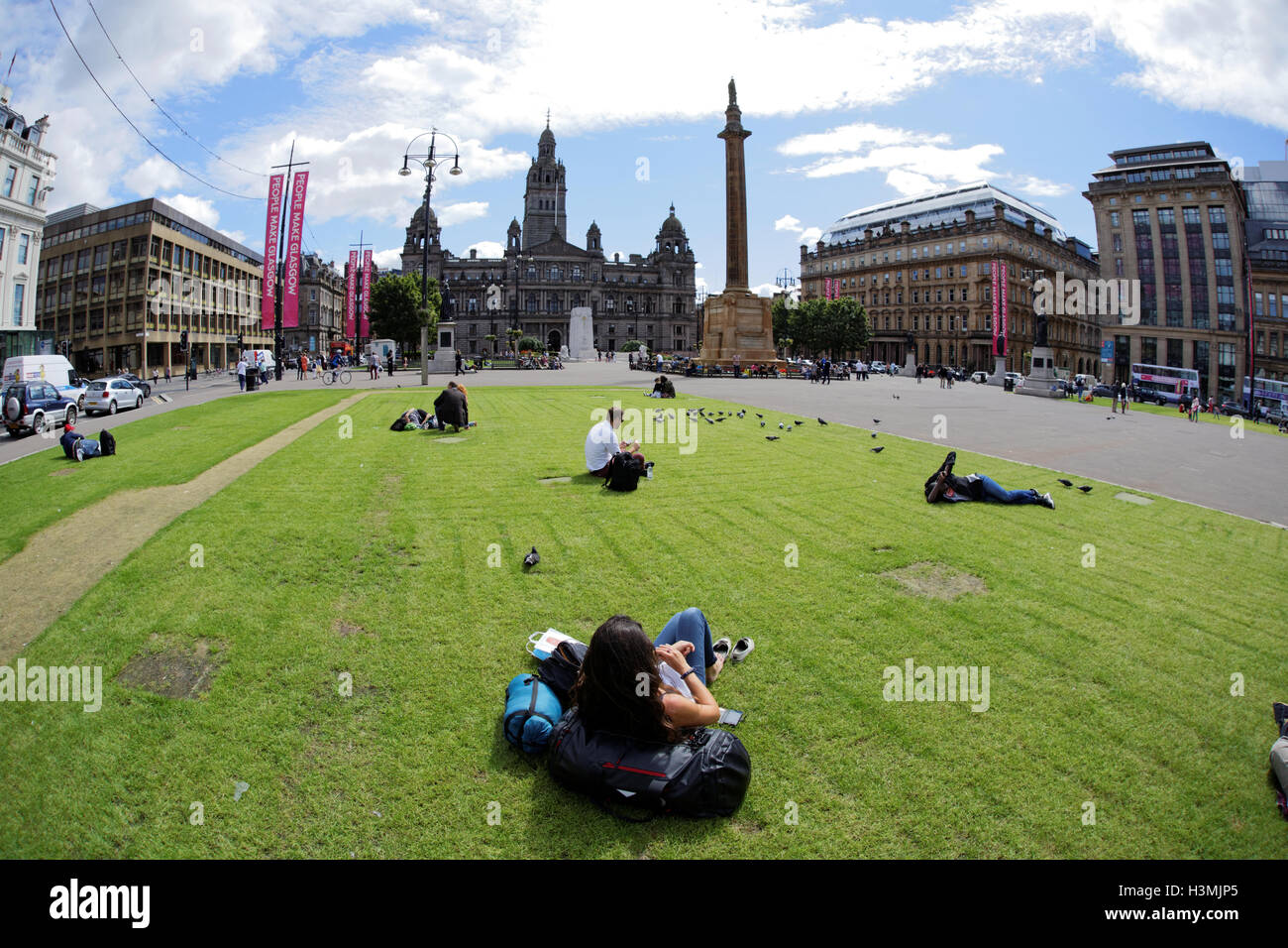 George Square and the city chambers with the cenotaph in Glasgow city center  centre locals and tourists relax and enjoy the sun Stock Photo