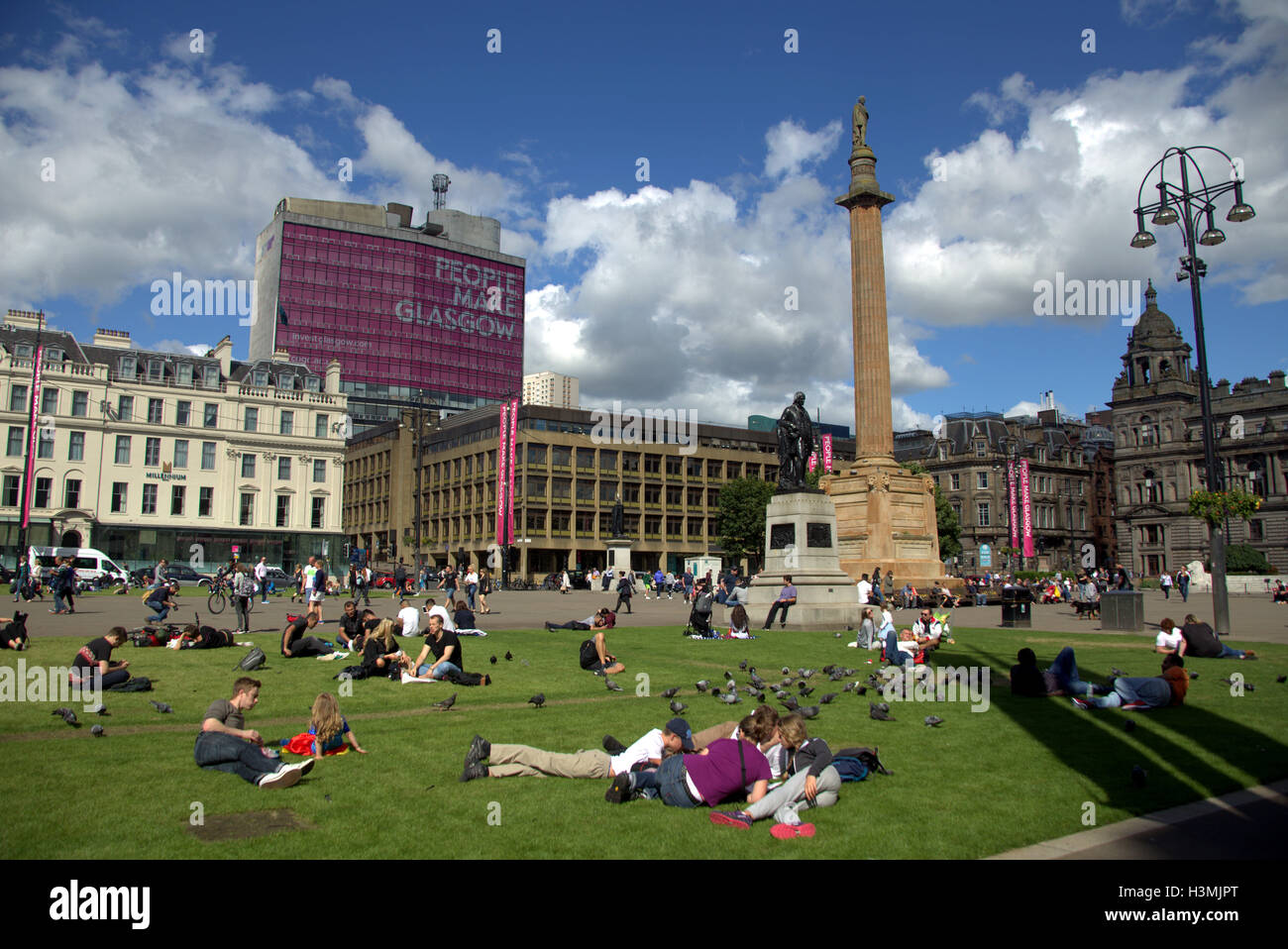 George Square and the city chambers with the cenotaph in Glasgow city center  centre locals and tourists relax and enjoy the sun Stock Photo