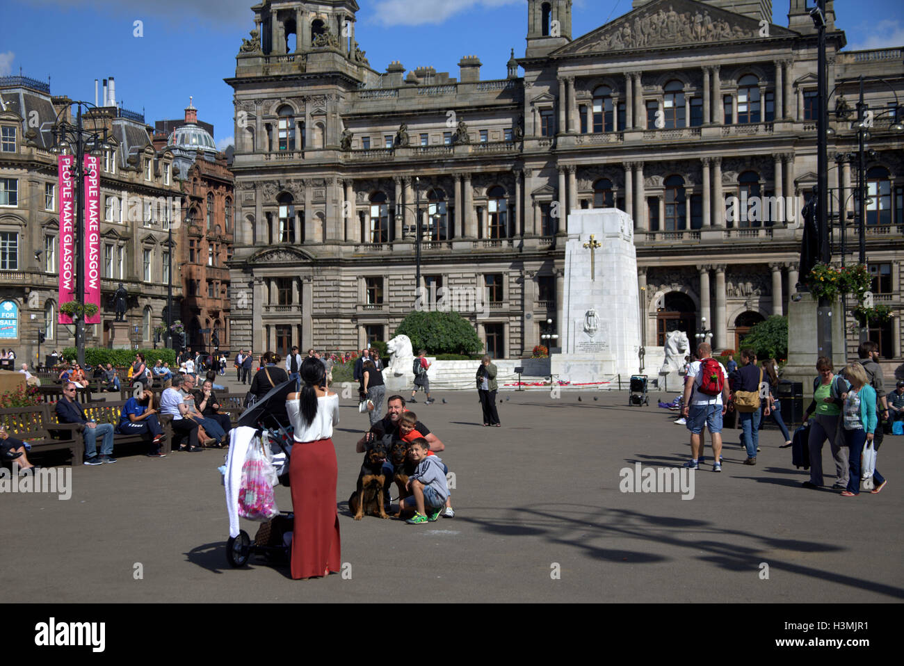 George Square and the city chambers with the cenotaph in Glasgow city center  centre locals and tourists relax and enjoy the sun Stock Photo